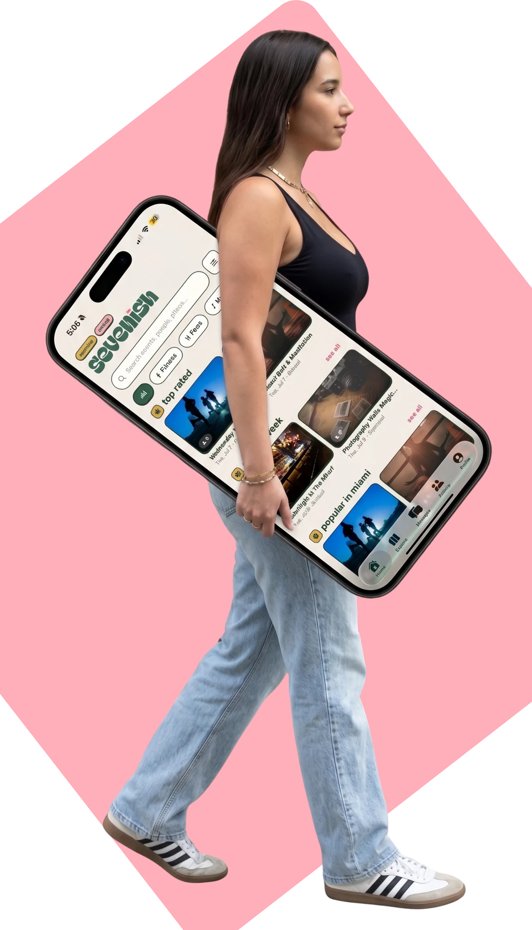 A woman walking while carrying an oversized phone showing the Sevenish feed of Miami plans