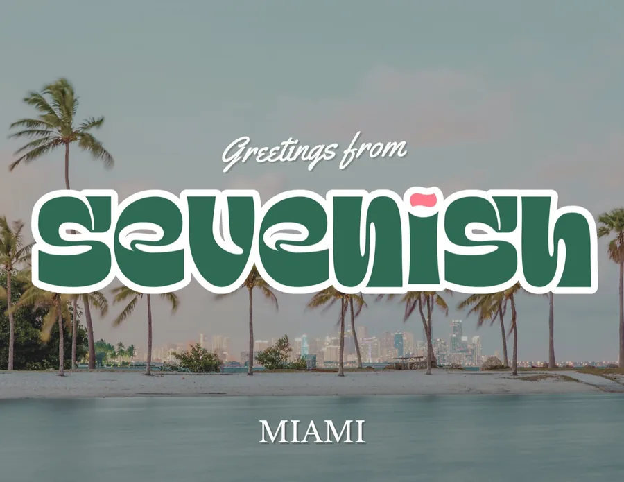 Postcard front: Greetings from Sevenish, Miami, over a palm-lined beach and the downtown skyline at dusk